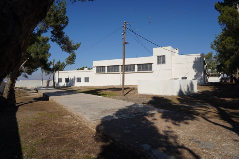 A restored schoolhouse under pine shade